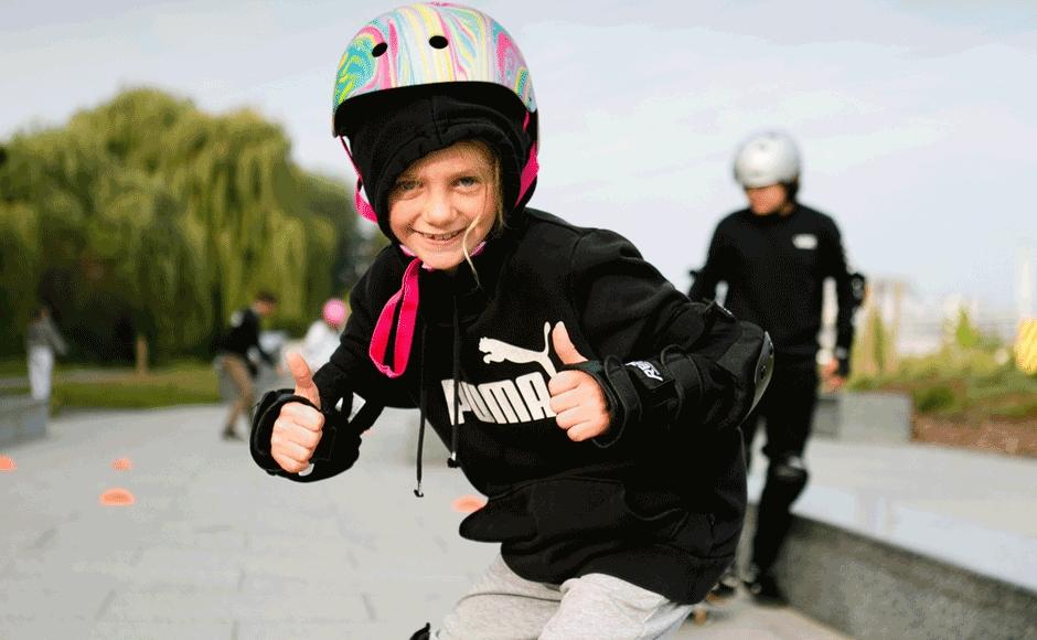 A child with their thumbs up skating