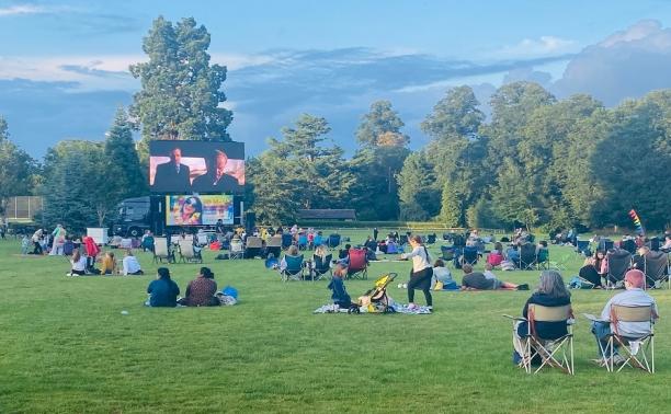 People sit in Woodside Park watching a film